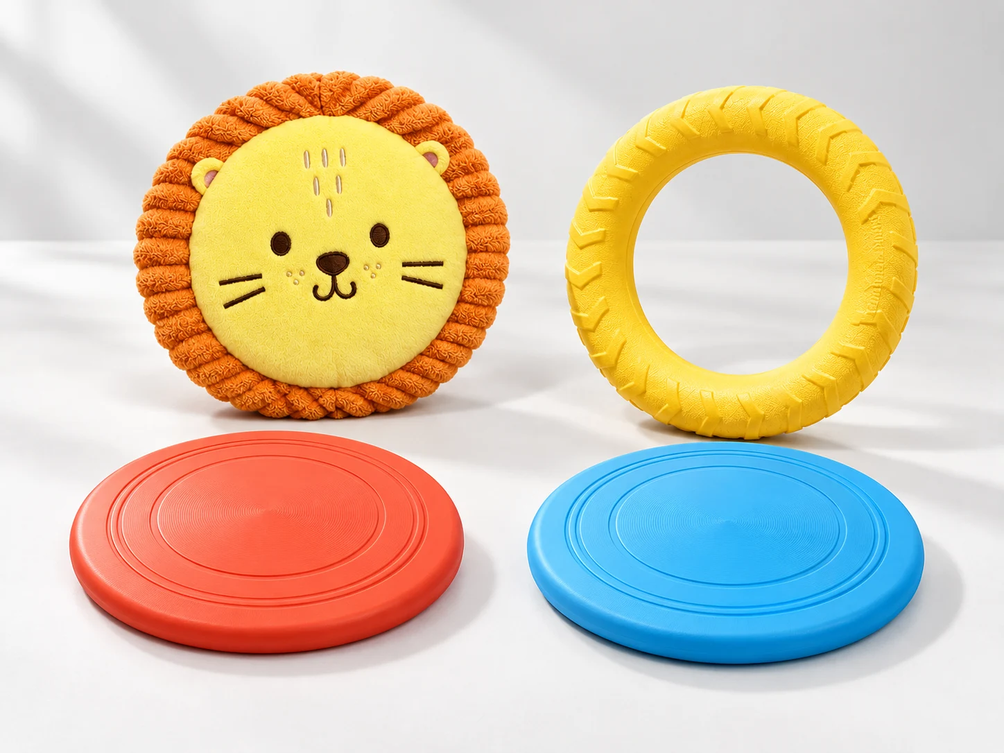 Four dog flying disc styles including a lion plush disc, yellow textured fetch ring and coral and blue round training discs