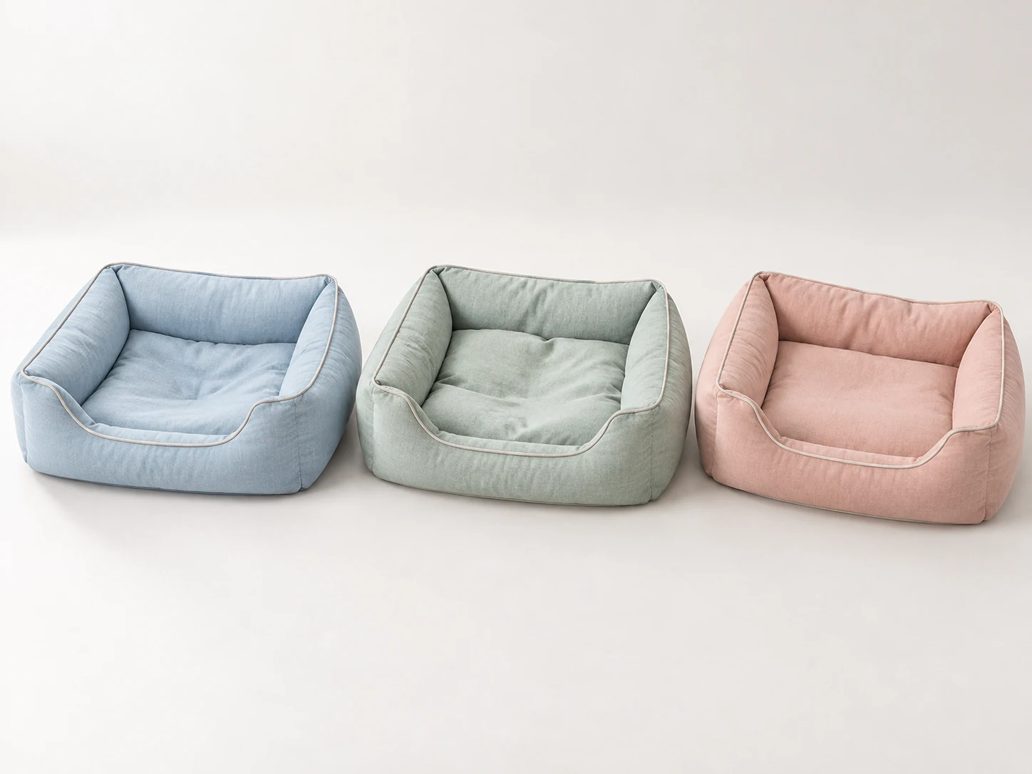 Three pastel blue, sage green and blush pink cushioned bolster dog beds