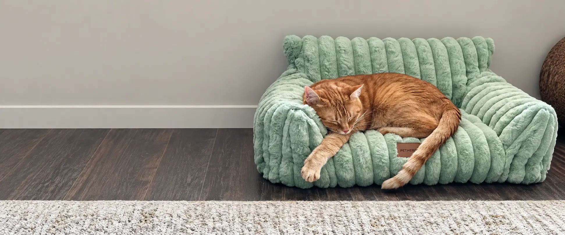 Ginger cat sleeping in a soft green cat bed.