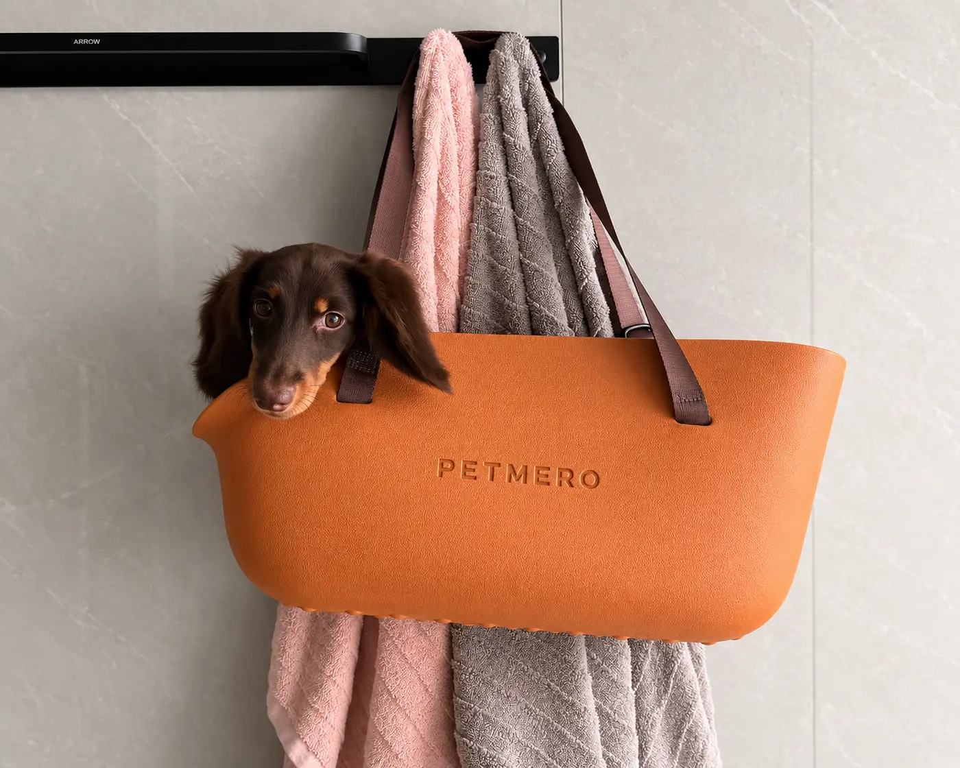 Dachshund sitting inside an orange pet carrier tote bag.