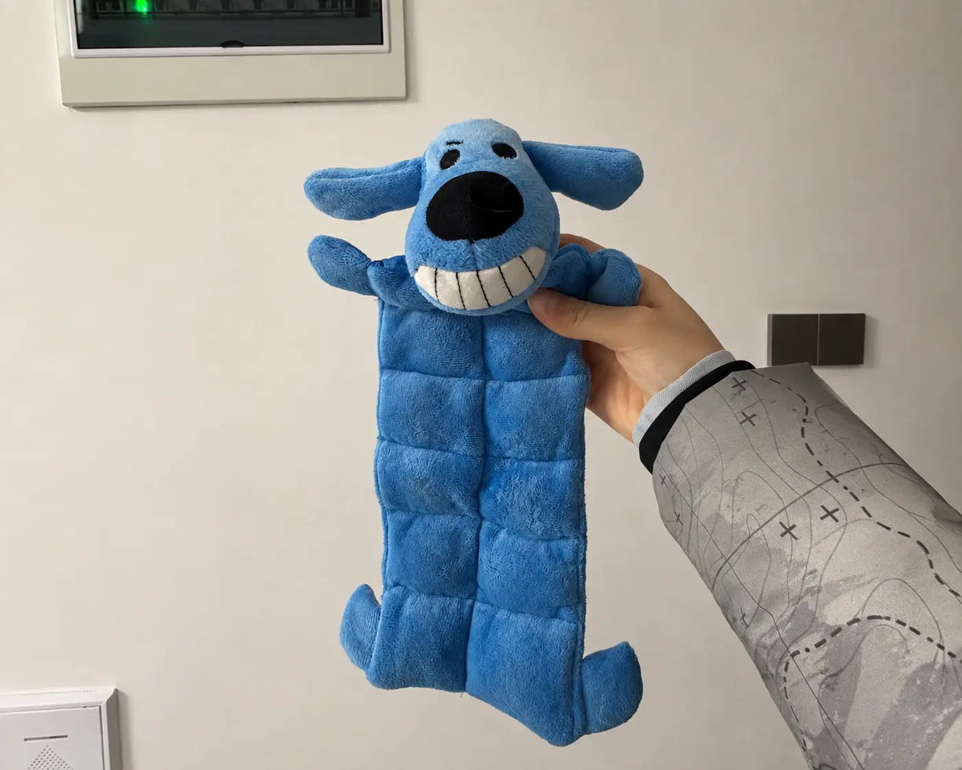 Completed blue dog-shaped plush toy sample held for review.