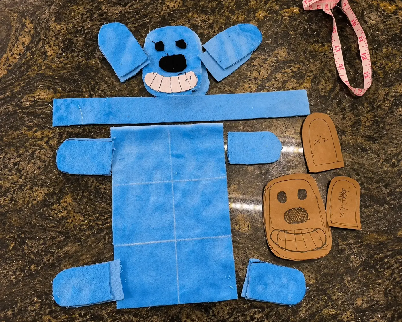 Blue dog-shaped plush toy fabric panels beside sewing pattern pieces.