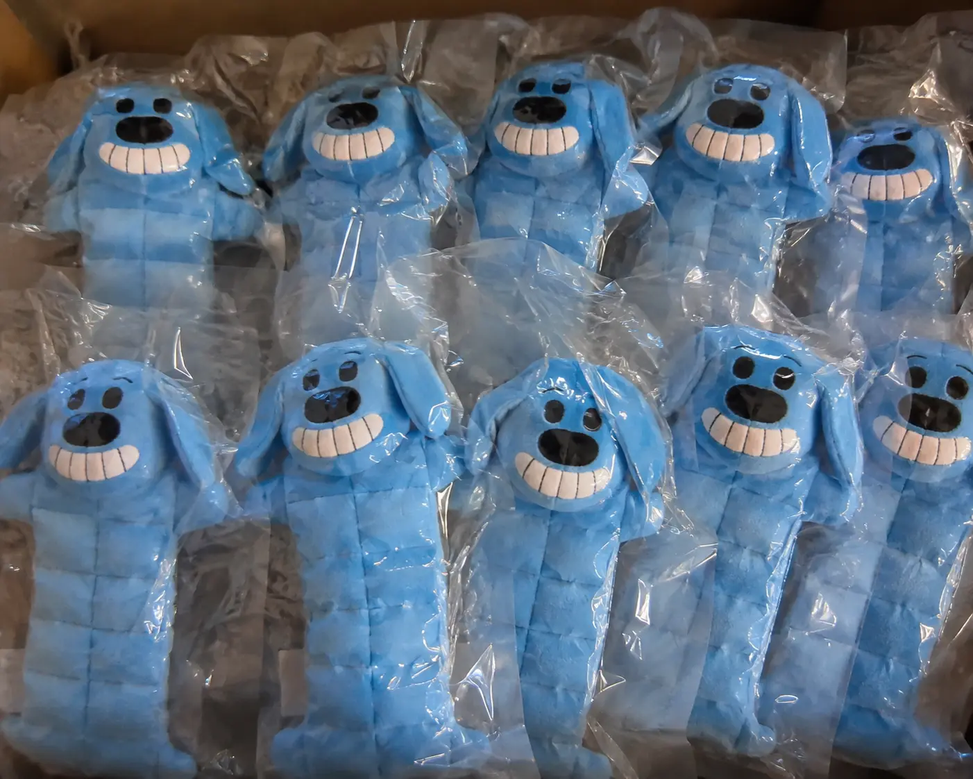 Matching blue plush dog toys individually packed in transparent bags.
