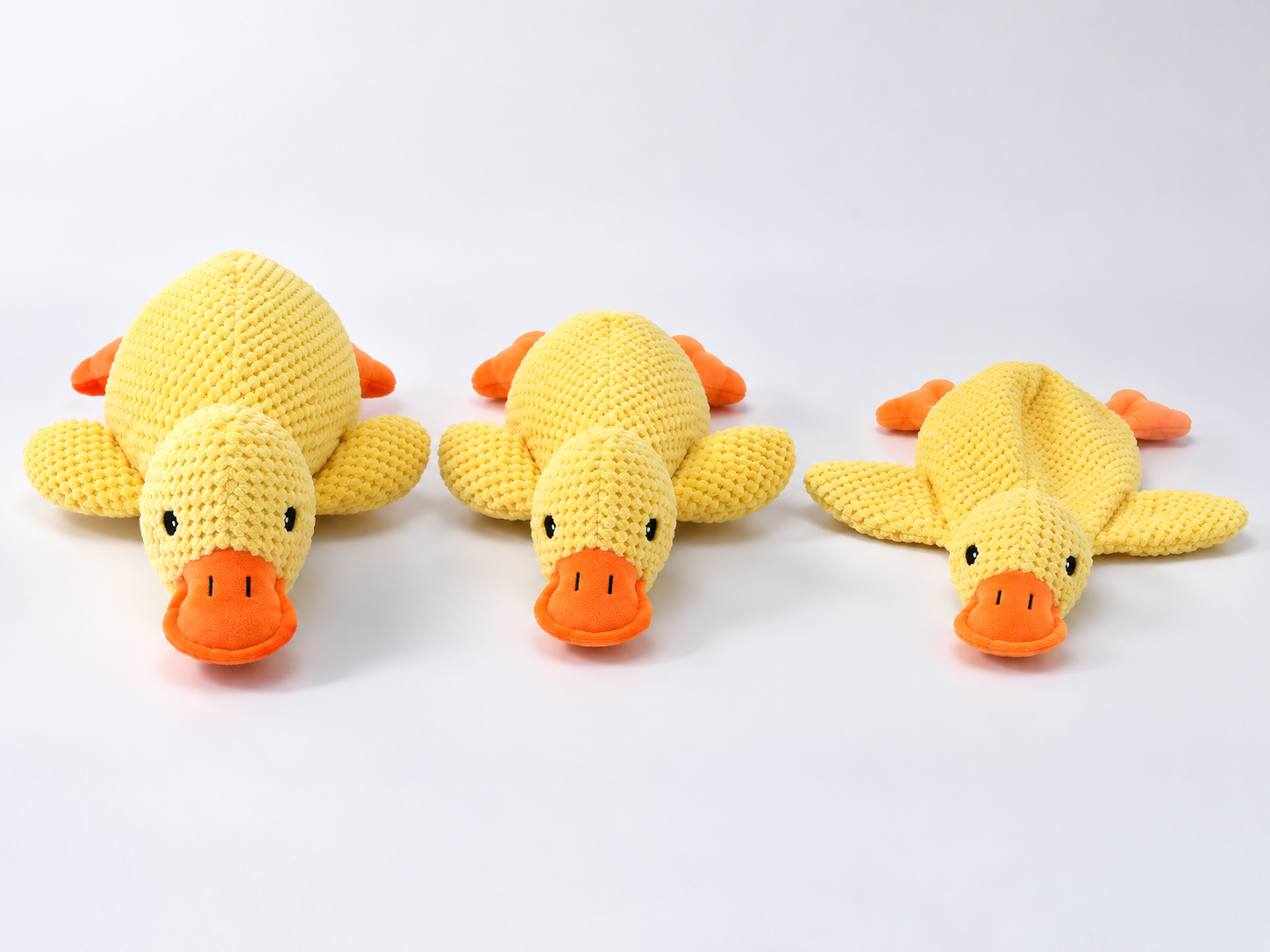 Three yellow plush duck dog toys showing full, reduced and flat stuffing profiles.